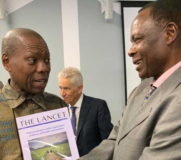 a colleague holding a copy of The Lancet while talking with another colleague